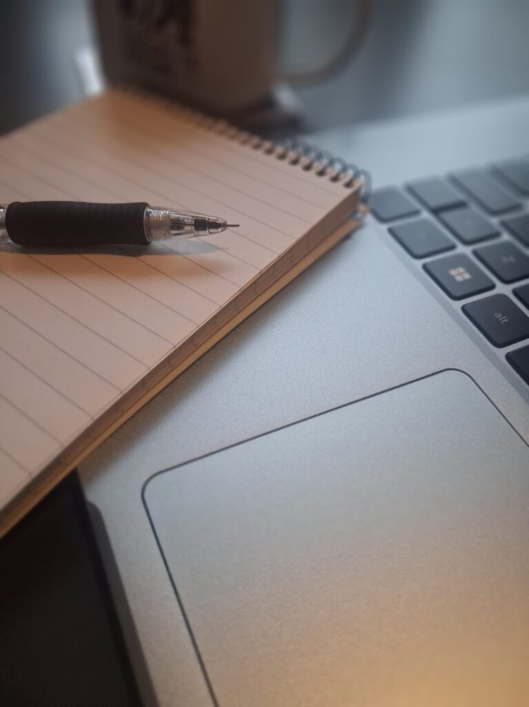 Workspace with laptop, notebook, and pen while planning an ExitLab eBook Project for Amazon KDP.