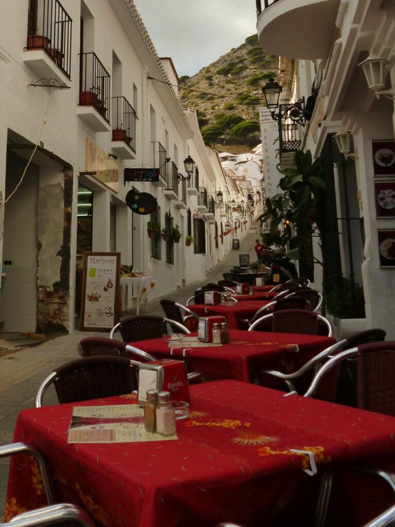 Outdoor restaurant tables in a narrow Spanish street reflecting modern lifestyle and the cost of convenience
