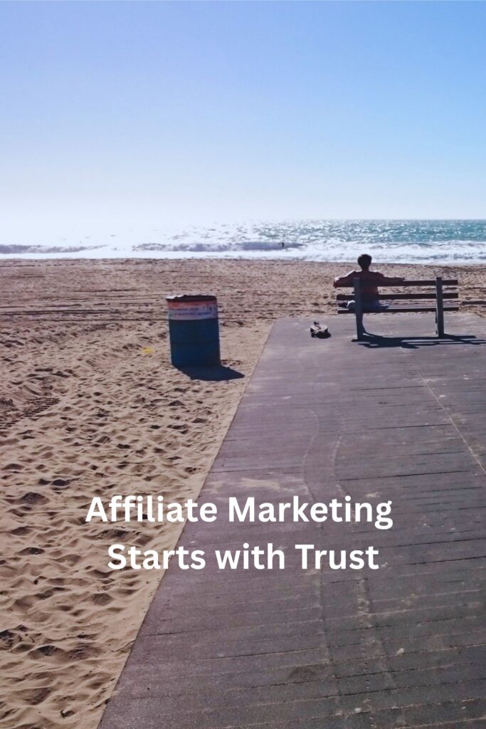 Person sitting on a bench overlooking the ocean, symbolizing the freedom that can come from building an affiliate marketing business based on trust.